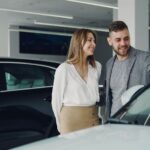 Uśmiechnięta para ogląda samochód rodzinny w salonie