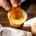 Chrupiący nugget zanurzany w kremowym żółtym sosie